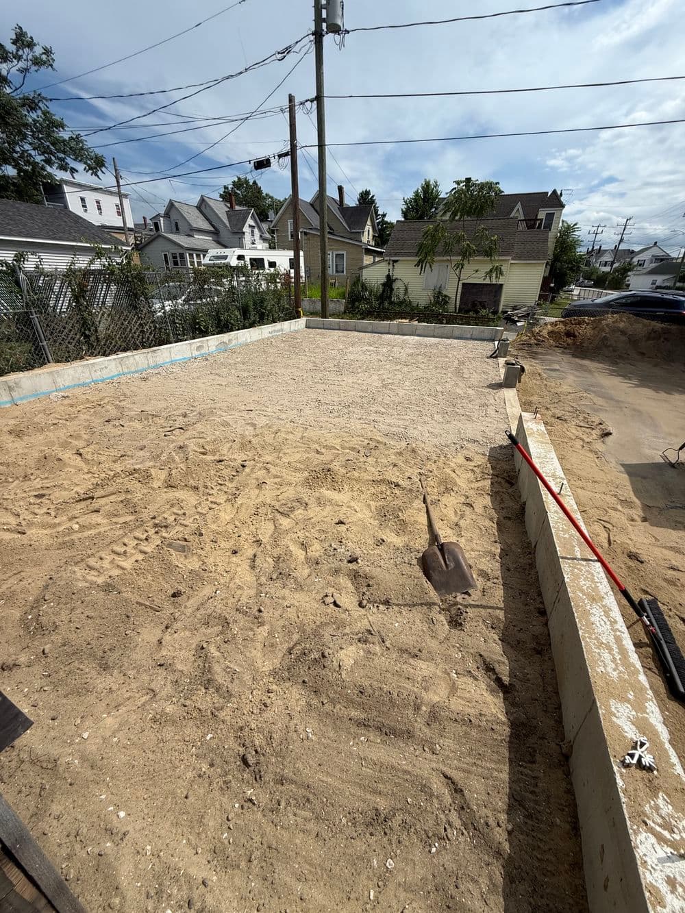 Construction site with freshly leveled sand foundation ready for building, utility poles visible.