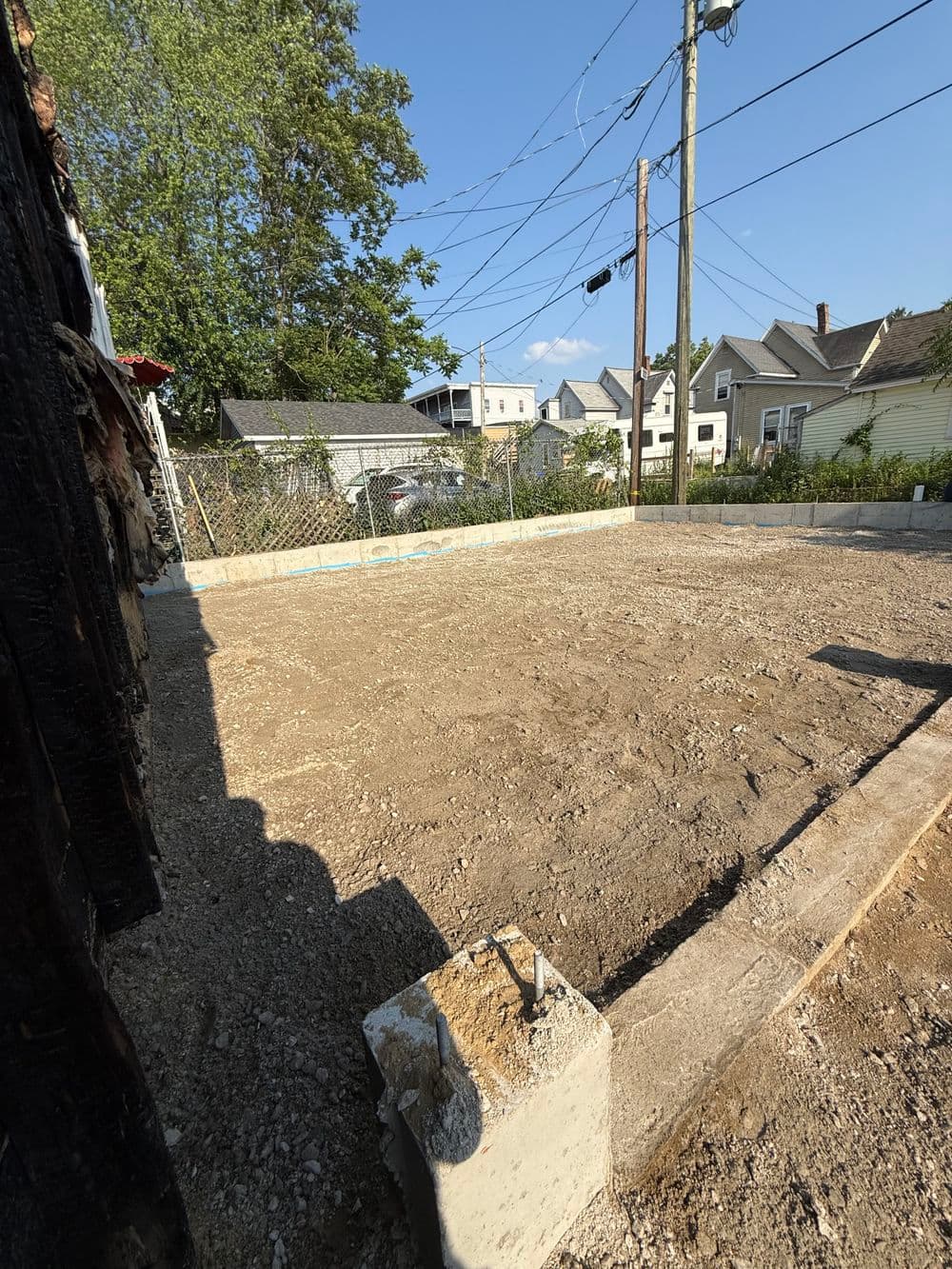 Construction site with gravel base and concrete foundation, surrounded by residential buildings.