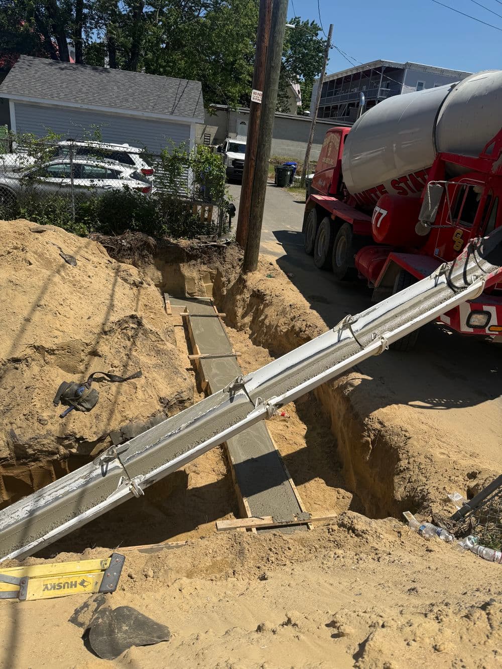 Concrete pouring in a trench near a cement truck at a construction site.